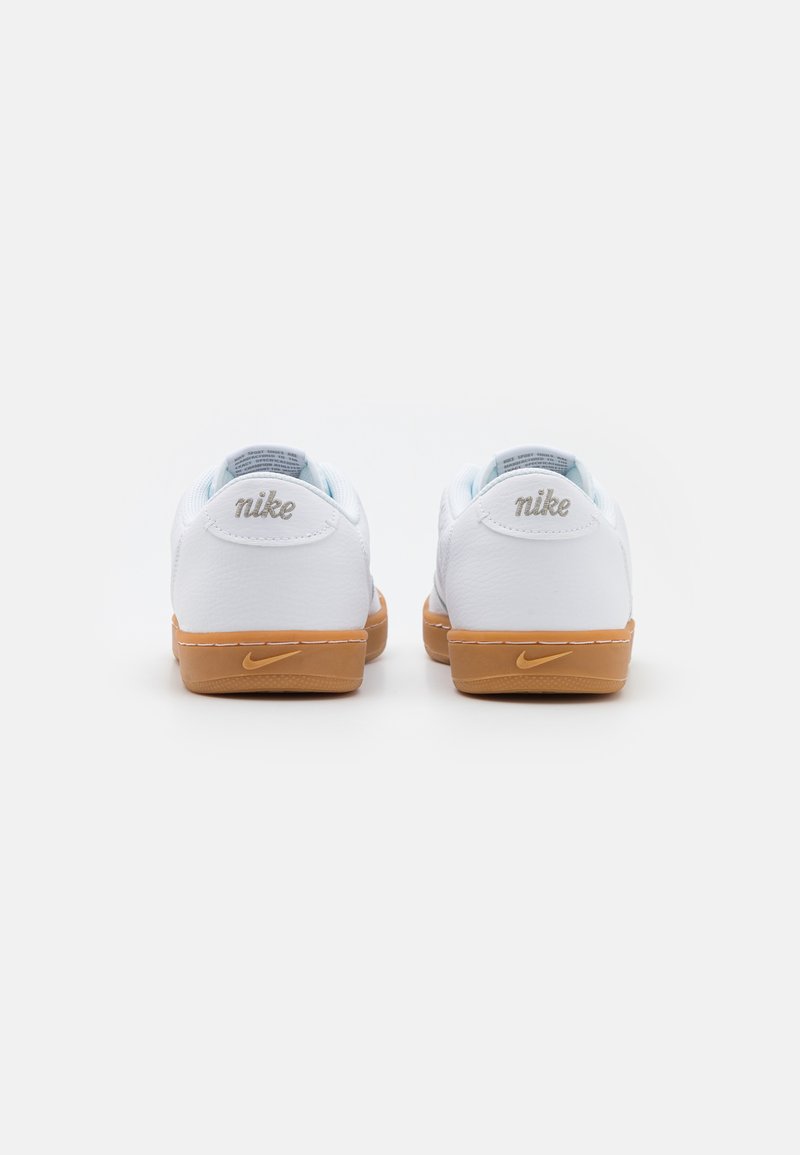 Białe skórzane sneakersy Nike z jasnoniebieskimi akcentami, z gumową podeszwą i haftowanym logo na pięcie. Klasyczny niski model.