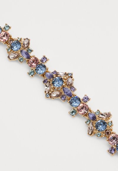 Bracelet doré avec des pierres semblables à des gemmes dans des nuances de bleu, violet et rose, de formes et tailles variées disposées en un motif floral.
