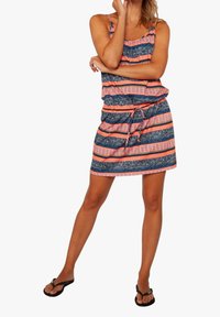 Hihaton mekko, jossa on kiristetty vyötärö ja sekoitus laivastonsinisiä, korallinvärisiä ja valkoisia heimokuoseja. Valmistettu kevyestä kankaasta.