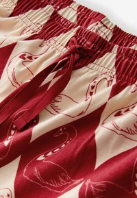 Red and cream cotton shorts featuring a swan print, with an elasticated waistband and drawstring detail.