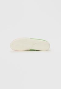 Zool van een sneaker met roze en groene accenten, een gedetailleerd profielpatroon en een klein reliëf Puma-katlogo in het midden.