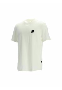 Cremefarbenes Kurzarm-T-Shirt mit Rundhalsausschnitt, das ein kleines schwarzes Logopatch auf der Brust und ein schwarzes Etikett am Saum trägt.