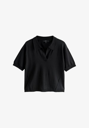 Melnas īsrokas polo krekls no mīksta auduma. Tam ir V veida kakla izgriezums, brīvs piegriezums un smalka šuves detaļa gar sāniem.