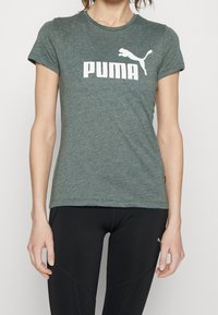 Grön ljung kortärmad t-shirt i mjukt tyg, med en framträdande vit "PUMA" logotyp och en hoppande puma-grafik på framsidan.