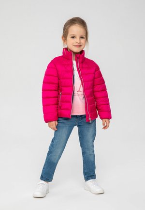 Giacca puffa fucsia con cuciture orizzontali, colletto alto, zip frontale e tasche laterali, indossata su una maglietta rosa chiaro e jeans blu.