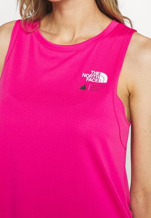 Woman wearing bright pink sleeveless top with The North Face logo and mountain graphic on the chest.