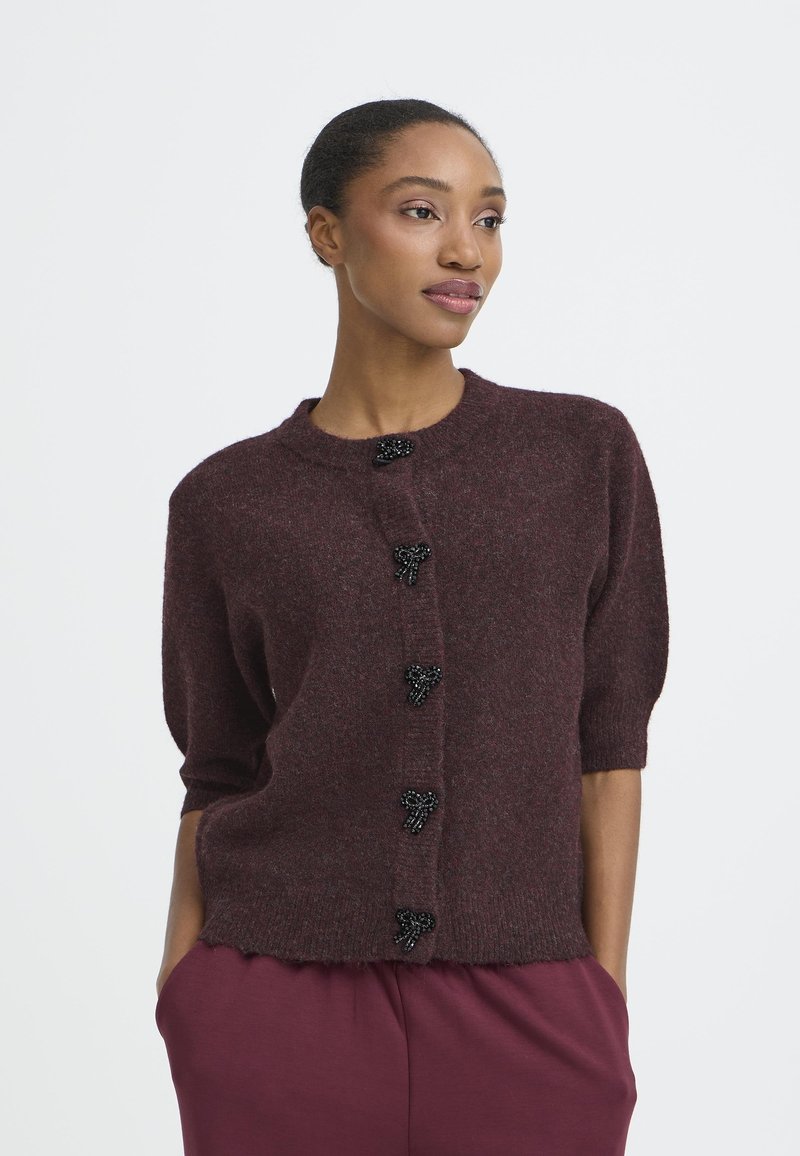 Cardigan in magenta a maglia con maniche corte, dotato di bottoni a forma di fiocco neri con perline e scollatura rotonda, tessuto testurizzato.