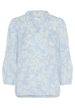 Svijetloplava bluzica s bijelim cvjetnim uzorkom, s volanima oko izreza i dugim rukavima. Mekani, lagani materijal s opuštenim krojem.