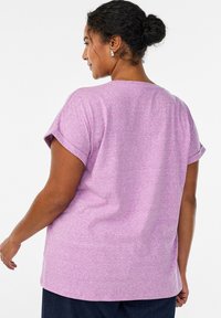 Fliederfarbenes Kurzarm-T-Shirt mit hochgekrempelten Ärmeln, lockerem Schnitt und glattem, strukturiertem Stoff. Rückansicht zeigt einen rundhalsausschnitt und einen geraden Saum.