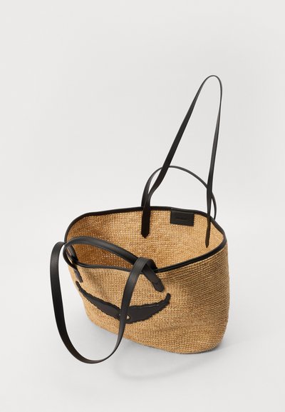 Geflochtene Stroh-Handtasche mit schwarzen Lederakzenten und -riemen. Offene Oberseite, runde Form, strukturierte Oberfläche und ein erhabenes Designelement.
