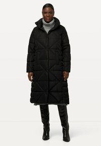 Abrigo puffer largo negro acolchado con collar alto, que presenta un patrón de diamantes, bolsillos laterales y un acabado texturizado.