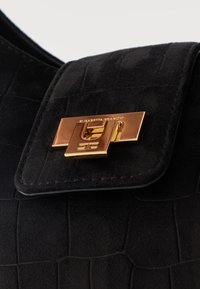 Μαύρο δερμάτινο καπάκι τσάντας με ανάγλυφη υφή και χρυσό ορθογώνιο κούμπωμα με στριφτή κλειδαριά.