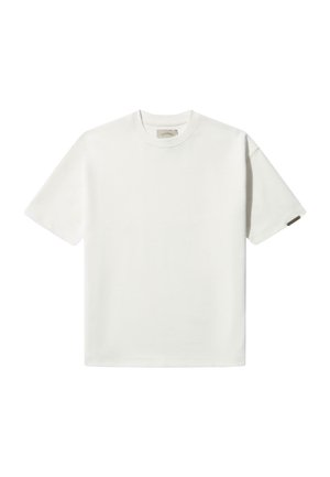 Trumpas rankovėmis baltas marškinėliai, pagaminti iš medvilnės, su apvalia iškirpte ir minimalistiniu dizainu, ant rankovės esantis nedidelis rudasis etiketė.