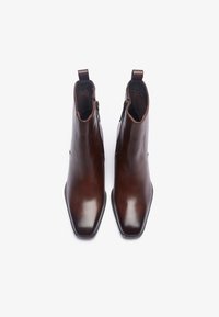Brown leather ankle boots with a sleek design, pointed toes, side zippers, and minimalistic stitching detail. Smooth texture and modern finish.