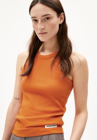 Débardeur orange à côtes sans manches avec un col rond et une étiquette arborant "ARMEDANGELS" sur l'ourlet. Texture lisse avec un léger extensibilité.