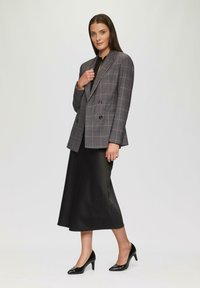 Grijze geruite double-breasted blazer met zwarte knopen, gecombineerd met een zwarte satijnen midi-rok en glanzende zwarte pointy heels. Soepele textuur.