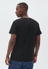 Sort bomulds T-shirt med korte ærmer og rund halsudskæring, der har en glat tekstur og en lige skæring i kanten.