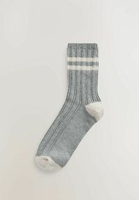 Szürke pamutzokni bordázott mintával, fehér csíkokkal a tetején és fehér orrszegéllyel. Kényelmet és jó illeszkedést biztosít.