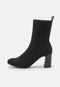 Schwarze Ankle Boots aus geripptem Stoff, mit spitzer Zehenform und dicker Absatz. Mit einer Zuglasche für einfaches An- und Ausziehen.