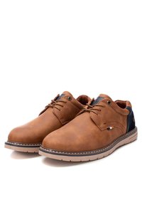 Zapatos de cuero marrón con una textura suave, que presentan acentos de color azul oscuro, diseño de cordones y una suela acolchada para mayor comodidad.
