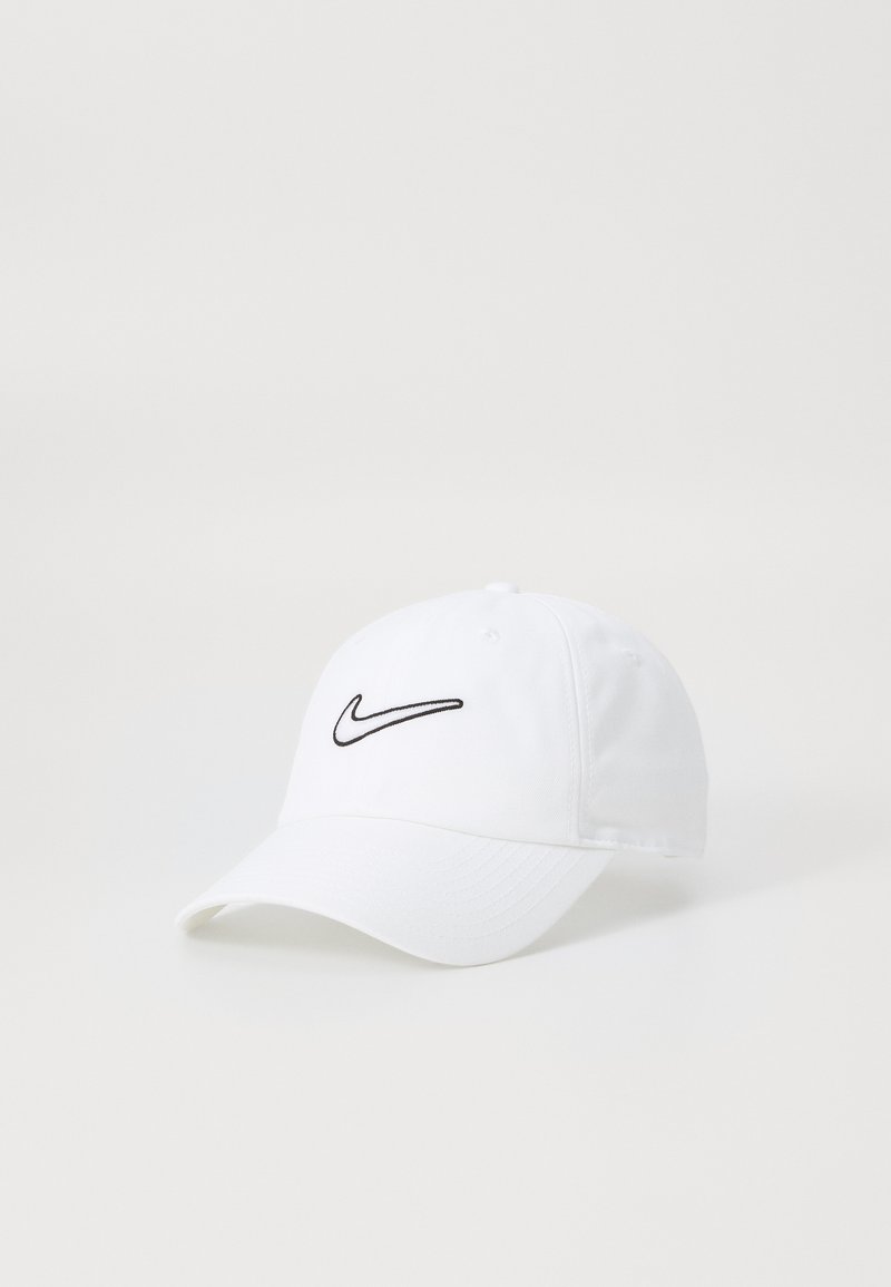 Hvid bomuldskepp med et sort broderet Nike-logo på fronten, en buet skygge, og seks ventilationsøje.