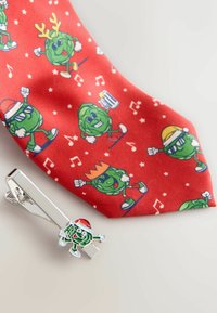 Rote Krawatte mit grünen Cartoonfiguren, die verschiedene Accessoires und Aktivitäten darstellen, kombiniert mit einer silbernen Krawattennadel, die eine Cartoonfigur mit einem Weihnachtsmannhut zeigt.