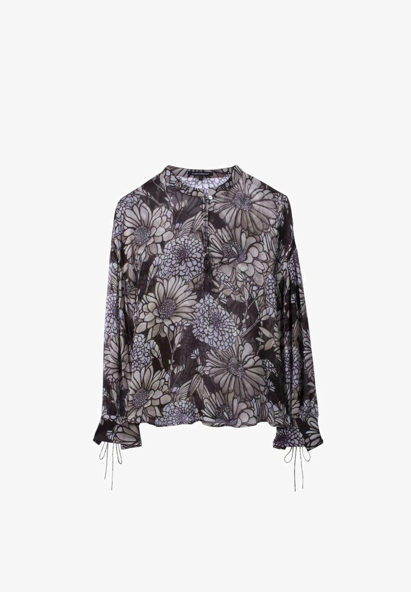 Blouse noire à manches longues avec grands motifs floraux gris, col rond, patte de boutonnage devant et poignets froncés avec détails noués.