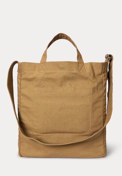 Μπεζ υφασμάτινη τσάντα ώμου με κοντά χερούλια και μακρύ, ρυθμιζόμενο ιμάντα ώμου, με μεγάλο μπροστινό τσέπη και εμφανείς ραφές.