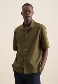 Camicia a maniche corte verde oliva in tessuto leggero, con colletto e chiusura a bottoni sul davanti con bottoni crema.