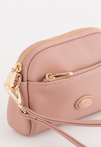 Bolso de cuero texturizado rosa con herrajes dorados, que cuenta con un cierre de cremallera y un bolsillo frontal. Incluye una correa de muñeca y detalle del logo de la marca.