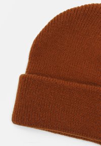 Gorro laranja tricotado com textura canelada e rebordo virado. Feito de material quente, apresentando um ponto uniforme em todo o seu comprimento.