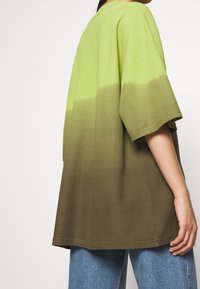 Zeleno-hnědé gradientové oversized tričko v lehkém materiálu, s krátkými rukávy a kulatým výstřihem, s texturovaným povrchem.