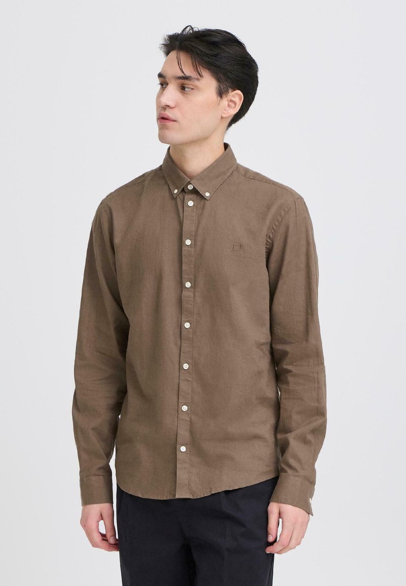 Chemise marron à manches longues en mélange de lin avec un col boutonné, ornée de boutons blancs et d'un petit logo brodé sur la poitrine.