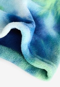 Couverture en polaire douce présentant un dégradé de teintes bleues et vertes, avec une texture pelucheuse et un bord roulé pour le confort.