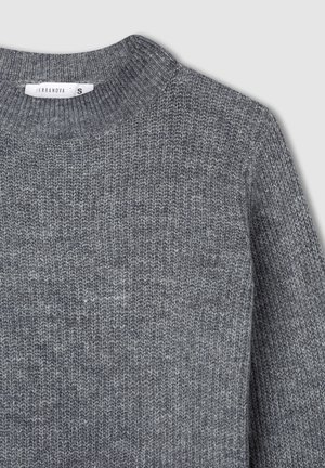 Szary prążkowany sweter z okrągłym dekoltem i małą białą metką rozmiaru "S" przy kołnierzu.