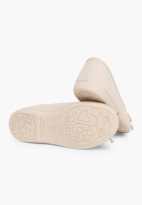 Chaussures en textile beige avec une semelle flexible arborant un motif en relief de fleurs et de cœurs. Couture renforcée et design à bout rond.