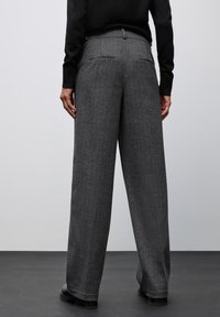 Pantalones de pierna ancha en gris con un patrón de pata de gallo, que cuentan con una cintura alta, bolsillos traseros y un acabado de tejido texturizado.