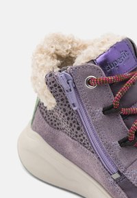 Bottes enfant en daim violet avec col en fourrure texturée, lacets contrastants, fermeture éclair sur le côté et sections à motifs. Semelle en caoutchouc durable.