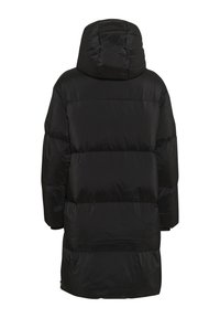 Čierna prešívaná bunda s kapucňou, ktorá má prešívaný design, spadnuté ramená a mierne lesklý povrch. Dĺžka dosahuje do polovice stehien.