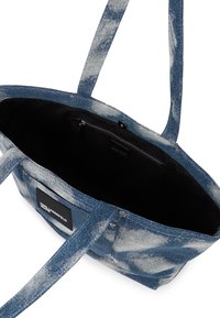 Denim torba s mekom teksturom, plavo-bijela gradijentna shema boja. Ima čvrste ručke i crni interijer s džepom na čipku.