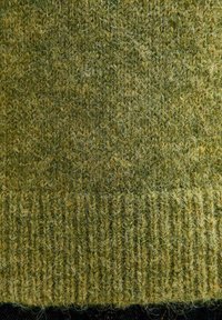 Tessuto di lana verde lavorato a maglia con una superficie textured e pelosa, bordato con una finitura a costine. Il colore varia dal verde scuro al verde chiaro.