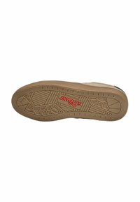 Semelle en caoutchouc brun avec un motif de grip texturé. Présente un logo rouge. La partie supérieure est de couleur beige clair, s'étendant jusqu'au bord de la chaussure.