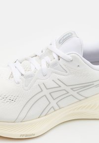 Scarpa atletica bianca con tomaia testurizzata e lacci. Presenta accenti grigi e un motivo a onda distintivo sulla suola. Marchio “FF Blast+” visibile.