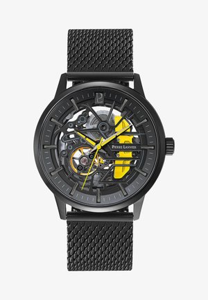 Montre squelette noire avec un bracelet noir texturé. Présente des accents jaunes et bleus sur le cadran et des composants de mouvement mécanique visibles.