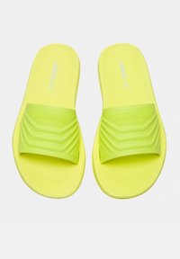 Bright yellow slides with a textured, ridged strap. Made from rubber, featuring a flat sole and embossed brand logo.
