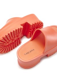 Oranje plastic strandslippers met een gestructureerde zool, brede banden en een plat ontwerp. Heeft een gladde afwerking en een reliëflogo aan de binnenkant.