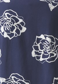 Marinblått tyg med stora vita blomstermönster som är jämnt fördelade i ett upprepande mönster.