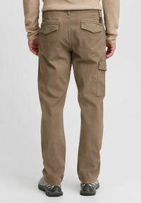 Brown cargo pants made from durable fabric, featuring a straight leg design, side pockets, and reinforced back pockets.