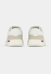 Λευκά και μπεζ αθλητικά παπούτσια με λείο δερμάτινο επάνω μέρος και σουέτ λεπτομέρειες, με λουρί έλξης και μικρή κόκκινη, λευκή και μπλε ρίγα.