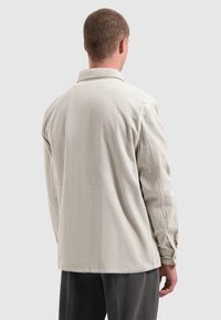 Lichtgrijze corduroy blouse met een kraag, lange mouwen en een rechte onderrand, voorzien van een verticale ribbeltextuur.